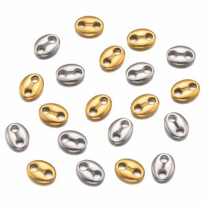 May include: A collection of oval-shaped metal connector charms in gold and silver tones. The charms have two holes on each side, allowing them to be attached to chains or other jewelry.