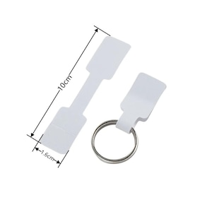May include: Two white paper tags with a metal ring. The larger tag is 10 cm long and 1.6 cm wide. The smaller tag is 1.6 cm wide.