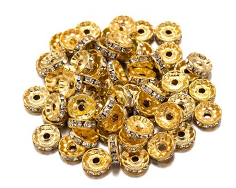 May include: A pile of gold-toned metal beads with clear rhinestones. The beads are round with a hole in the center.