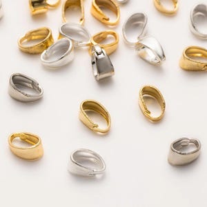 May include: A collection of gold and silver oval-shaped jump rings. The jump rings are used for attaching charms, pendants, or other jewellery components.