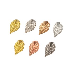 May include: Six metal leaf charms in different finishes: gold, silver, rose gold, and gunmetal. The leaves are detailed and have a textured surface.