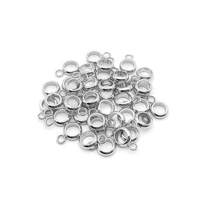 May include: A pile of silver-toned metal jump rings with a small loop on one side. The rings are approximately 1.2 cm in diameter.