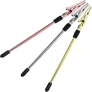 May include: Three long, thin metal clamps with black rubber tips. The clamps are gold, silver, and rose gold.