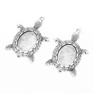 May include: Two silver turtle shaped pendant trays with oval shaped glass inserts. The turtles have detailed carvings on their shells.