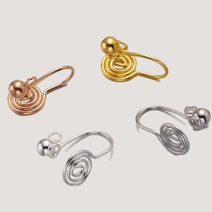 May include: Three pairs of spiral ear cuffs in gold, rose gold, and silver. Each cuff features a small ball at the top and a spiral design.