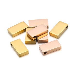 May include: A group of gold and rose gold metal bar charms with a hole for attaching to a necklace or bracelet.