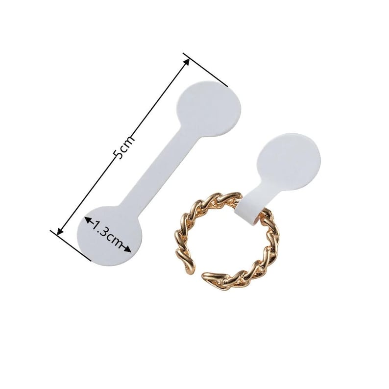 May include: Two white ring size stickers with a 1.3 inch diameter circle on one end and a 5 inch long strip. The stickers are designed to be attached to rings for sizing.