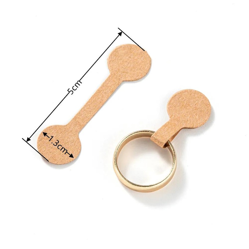 May include: Two brown paper ring sizing tags with a 1.3 inch diameter circle on each end and a 5 inch long strip connecting the circles. The tags are designed to be used for sizing rings.