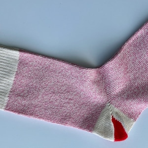 Puede incluir: Un calcet&iacute;n rosa y blanco con tal&oacute;n y puntera rojos. El calcet&iacute;n est&aacute; hecho de un tejido suave y de punto.