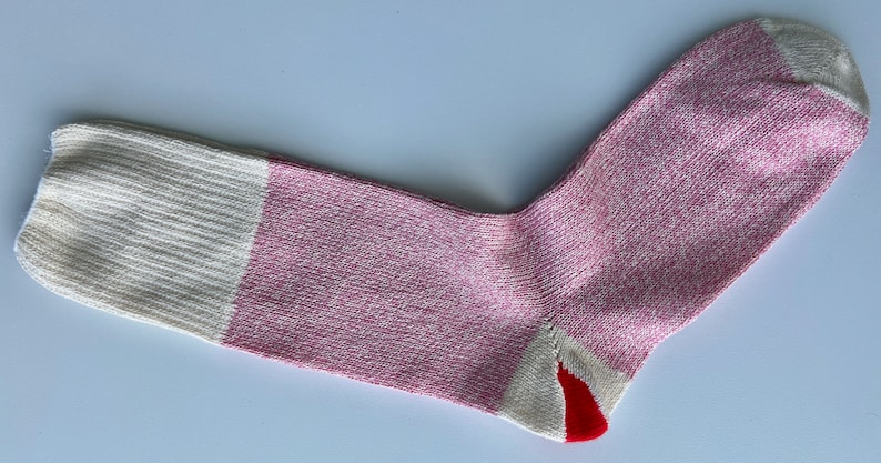 Puede incluir: Un calcet&iacute;n rosa y blanco con tal&oacute;n y puntera rojos. El calcet&iacute;n est&aacute; hecho de un tejido suave y de punto.
