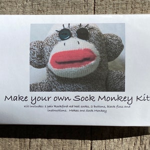 Puede incluir: Una tarjeta blanca con el texto "Make your own Sock Monkey Kit" y una foto de la cara de un mono de calcet&iacute;n. El texto debajo de la foto dice "Kit includes: 1 pair Rockford red heel socks, 2 buttons, black floss and instructions. Makes one Sock Monkey."