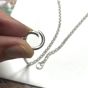 Op de afbeelding: Een zilveren ketting met een karabijn sluiting. De ketting is gemaakt van kleine, ronde schakels.