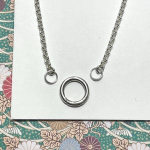 Op de afbeelding: Een zilveren ketting met twee springringen en een zilveren sluiting. De ketting is een delicate, fijne ketting.