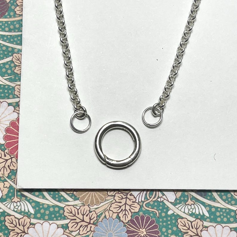 Op de afbeelding: Een zilveren ketting met twee springringen en een zilveren sluiting. De ketting is een delicate, fijne ketting.