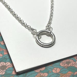 Op de afbeelding: Een zilveren ketting met een zilveren ringgesp. De ketting is een delicate, fijne ketting.