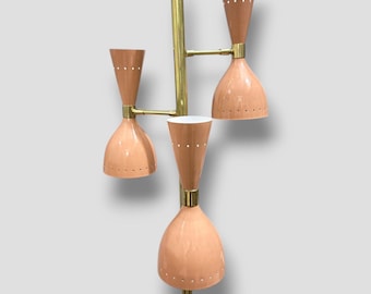 May include: A brass floor lamp with four peach-colored shades. The shades have a white interior and a pattern of small holes. The lamp has a mid-century modern design.