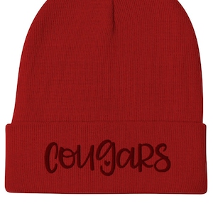 Puede incluir: Gorro de punto rojo con la palabra "Cougar" bordada en negro en la parte delantera.
