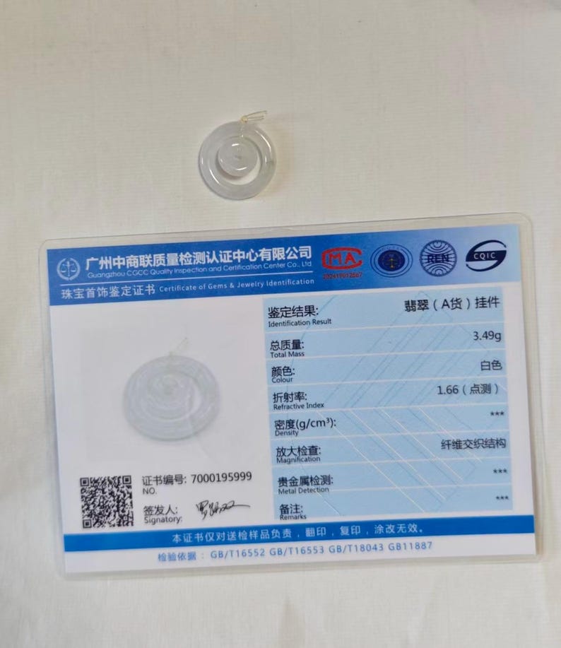 May include: A translucent white jade pendant shaped like a circular ring with a smaller center disc, accompanied by a rectangular identification certificate featuring blue borders, text in Chinese and English, and a total mass of 3.49g.
