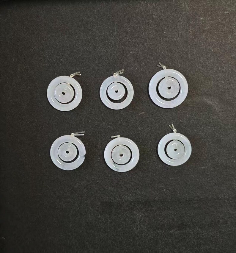 May include: Six circular pendants featuring a double-ring design. Each pendant consists of a larger outer ring and a smaller inner ring, both crafted from a pale, translucent white material. Each piece includes a small silver-toned metal bail.