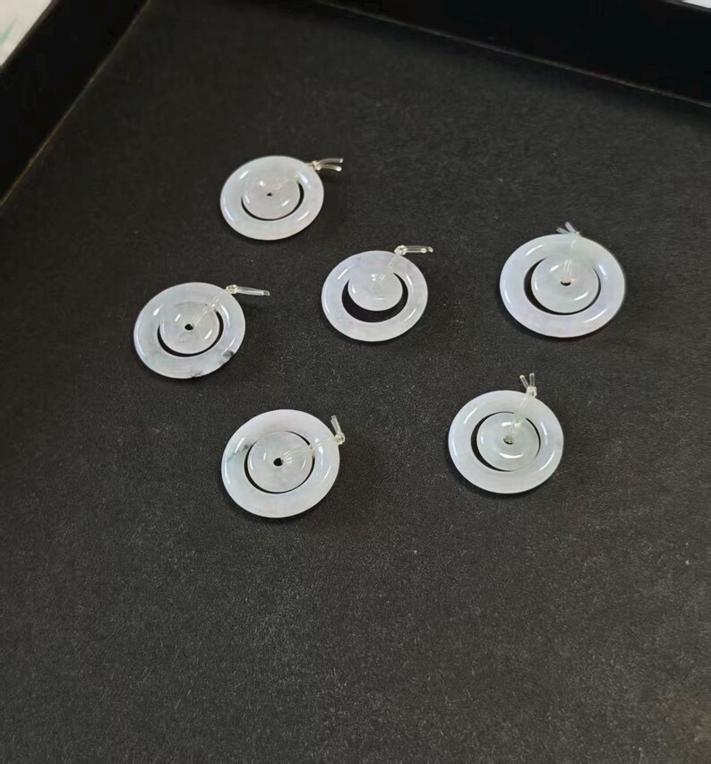 May include: Six circular white jade pendants, each featuring a smaller concentric ring suspended within a larger outer ring. These smooth, polished stone charms have a translucent appearance and include a small silver-toned metal bail at the top.
