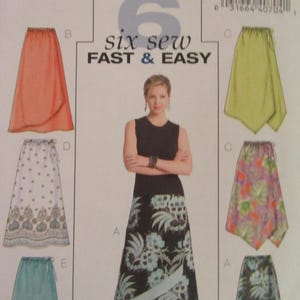 May include: A sewing pattern for six different wrap skirts. The pattern is for sizes 8-10-12-14. The skirts are shown in various colors and patterns, including coral, white with a floral print, teal, and black with a floral print.
