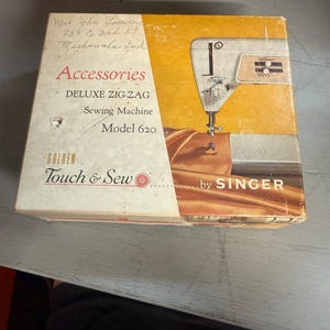 May include: A rectangular cardboard box for a Singer Golden Touch & Sew Deluxe Zig-Zag Sewing Machine Model 620. The box features a yellow and white color scheme with an illustration of the sewing machine and the text Accessories and by SINGER.