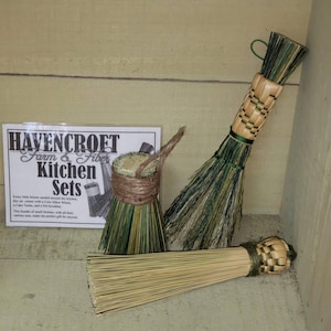 May include: Three handmade kitchen brushes with natural fiber bristles and woven handles. The brushes are green, brown, and natural in color. The text on the card reads "Havencroft Farm & Fiber Kitchen Sets".