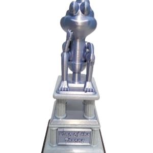 May include: A silver 3D printed figurine of a frog sitting on a throne with the words "King of the Throne" inscribed on the base.