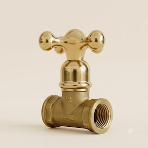 May include: A polished brass faucet valve featuring a cross-shaped handle and a T-shaped body. The metal component displays the text 1/2 and an arrow symbol indicating flow direction, with a threaded opening visible on the right side of the base.