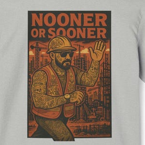 以下が含まれることがあります： グレーのTシャツ。タトゥーを入れた建設作業員のグラフィックで、ヘルメットとサングラス、安全ベストを着用しています。「Nooner or Sooner」の文字が作業員の上にあります。背景には建設現場が描かれています。