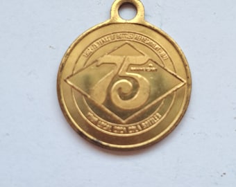 May include: A gold-colored metal medallion with a raised number "75" in the center. The medallion has a diamond shape with the text "1924-1999 75 YEARS OF BOTTLED BEER 1999-2017" around the edge.