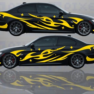 Könnte beinhalten: Ein schwarzes Auto mit gelben Flammen- und Sternenaufklebern. Das Auto ist eine Limousine mit sportlichem Design.