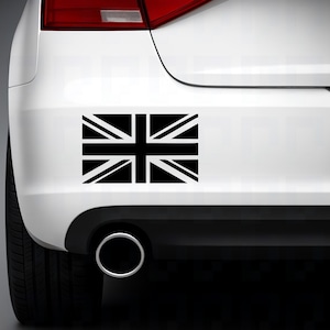 Peut inclure: Un autocollant noir représentant le drapeau Union Jack sur l'arrière d'une voiture blanche. Le drapeau est une représentation graphique du drapeau national du Royaume-Uni, avec des lignes blanches et noires symétriques.