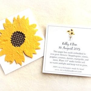 May include: A white card with a yellow sunflower made of seed paper. The card has text that reads "Kelly & Ben 16 August 2015" and explains that the paper has seeds embedded in it to grow flowers. The text also includes instructions for planting the paper.
