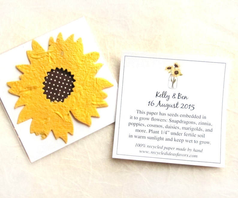 May include: A white card with a yellow sunflower made of seed paper. The card has text that reads "Kelly & Ben 16 August 2015" and explains that the paper has seeds embedded in it to grow flowers. The text also includes instructions for planting the paper.