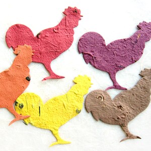 Puede incluir: Cinco recortes de gallo de papel en diferentes colores: rojo, naranja, morado, amarillo y marr&oacute;n. Los gallos est&aacute;n todos mirando hacia el lado derecho de la imagen.