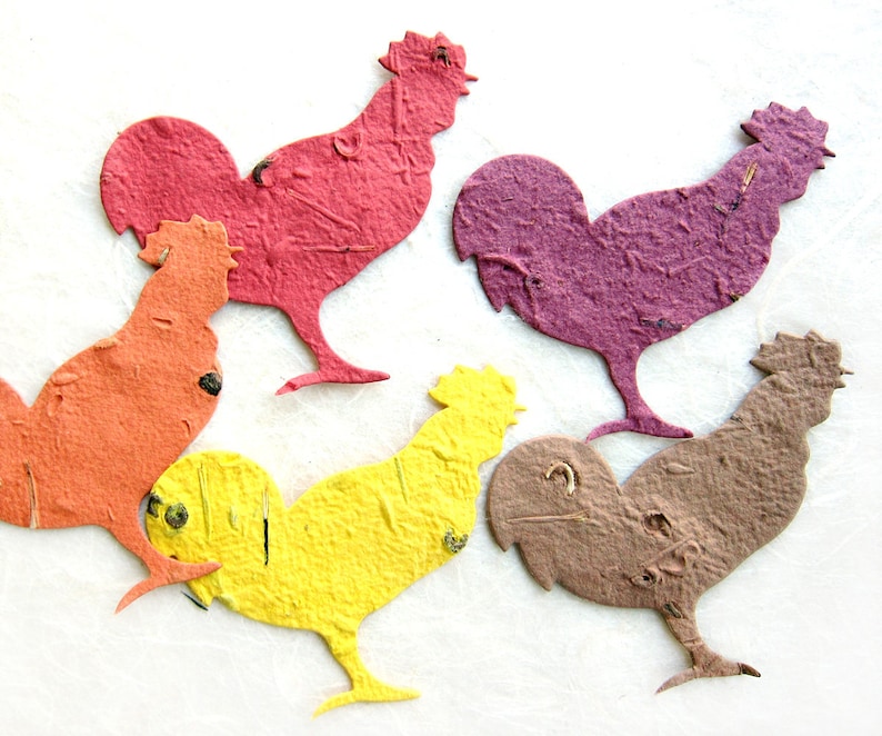 Puede incluir: Cinco recortes de gallo de papel en diferentes colores: rojo, naranja, morado, amarillo y marr&oacute;n. Los gallos est&aacute;n todos mirando hacia el lado derecho de la imagen.