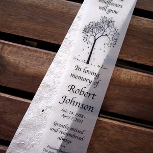 May include: A white paper bookmark with a black tree silhouette and the text "Plant this paper and wildflowers will grow."  The bookmark also includes the text "In loving memory of Robert Johnson July 14, 1958 - April 7, 2011 Greatly missed and remembered always... Planting Instructions: The paper piece has seeds for growing an assortment of pretty garden flowers. Keep the paper damp for a period of 7-10 days and watch it grow!"