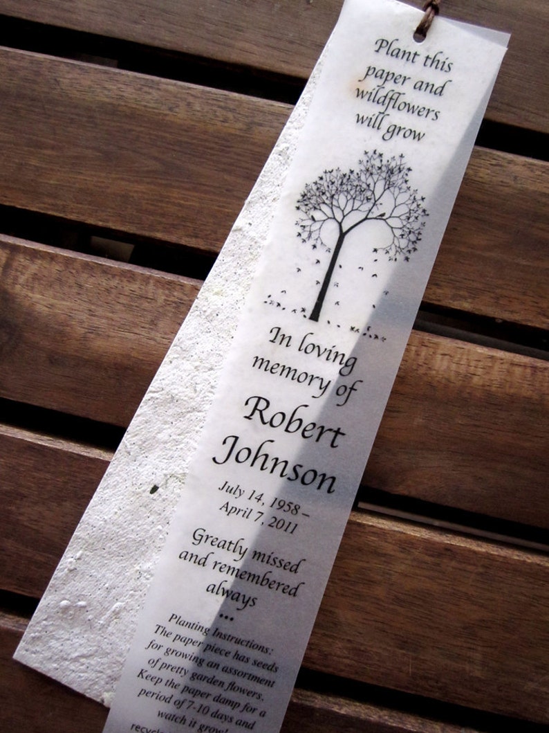 May include: A white paper bookmark with a black tree silhouette and the text "Plant this paper and wildflowers will grow."  The bookmark also includes the text "In loving memory of Robert Johnson July 14, 1958 - April 7, 2011 Greatly missed and remembered always... Planting Instructions: The paper piece has seeds for growing an assortment of pretty garden flowers. Keep the paper damp for a period of 7-10 days and watch it grow!"