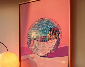 May include: A framed painting of a silver disco ball on a pink background. The disco ball is reflecting light and casting a shadow on the pink surface.