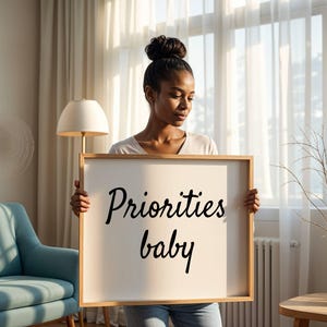 May include: A person holding a white sign with black lettering that says "Priorities baby".