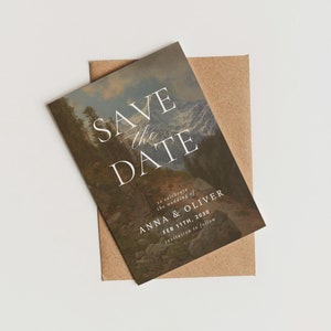 May include: Save the Date card with a mountain landscape background. The text reads "Save the Date" with a cursive "the" and "to celebrate the wedding of Anna & Oliver Feb 11th, 2030 invitation to follow."