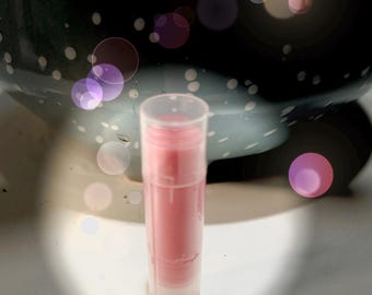 May include: A clear tube with a pink lip balm inside. The lip balm is a solid, opaque pink color.