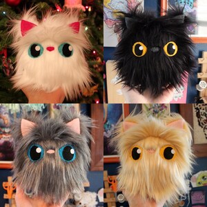 May include: Four plush toys shaped like cats with different fur colors and textures. The cats have large, round eyes and are all looking at the camera.