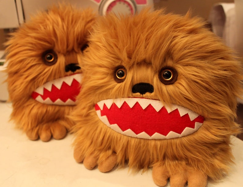 May include: Two brown furry plush toys with large, toothy grins. The toys have red felt mouths with white teeth and black noses.