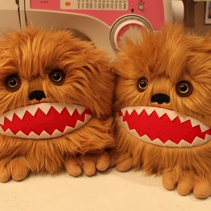 May include: Two brown furry plush toys with red mouths and white teeth. The toys have large brown eyes and black noses.