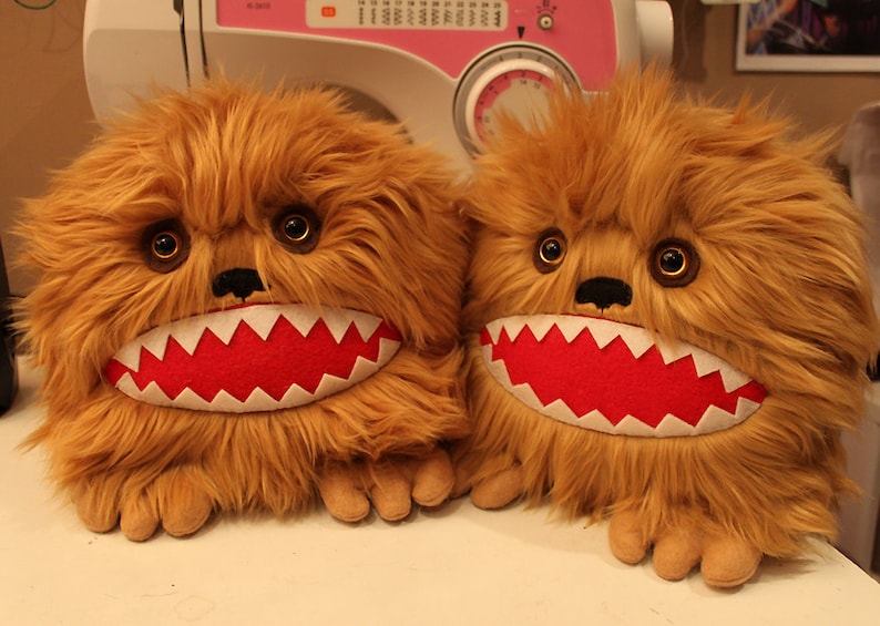 May include: Two brown furry plush toys with red mouths and white teeth. The toys have large brown eyes and black noses.