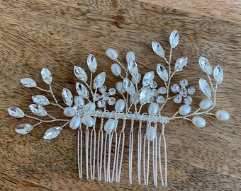 May include: A silver hair comb with a floral design featuring white pearls and rhinestones.