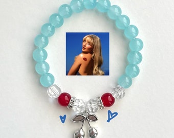 May include: A light blue beaded bracelet with red and clear beads and a silver cherry charm.