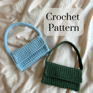 Può includere: Due borse a mano all'uncinetto, una blu chiaro e una verde scuro, su uno sfondo di tessuto beige. L'immagine include il testo "Crochet Pattern".